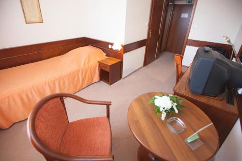 a hotel room with a bed and a table and a tv at Arany Bárány Hotel in Zalaegerszeg
