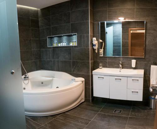 a bathroom with a large tub and a sink at Hotel Jelena in Banja Luka