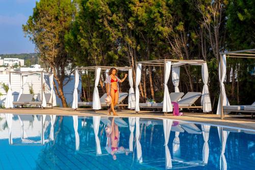 a woman and a child standing next to a swimming pool at Leonardo Crystal Cove Hotel & Spa – Adults only in Protaras
