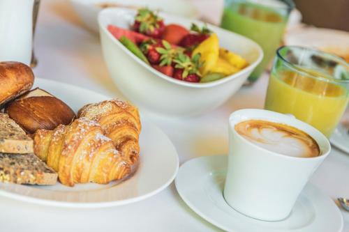 a table with a plate of pastries and a bowl of fruit at Hidalgo Suites in Postal