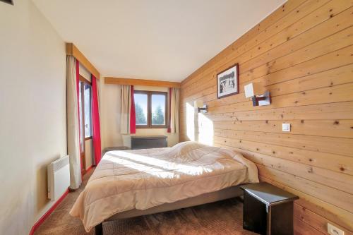 1 dormitorio con 1 cama en una pared de madera en Residences Quartier Falaise - maeva Home en Avoriaz