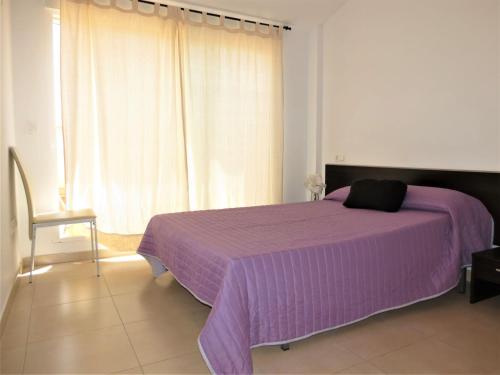 a purple bed in a white room with a window at Edificio Amanecer in Alcossebre