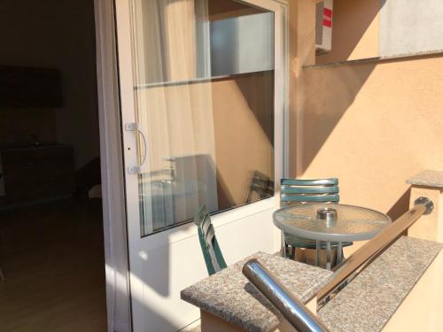 a small table and chairs next to a glass door at Apartman Polegubic in Biograd na Moru