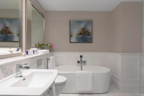 a white bathroom with a tub and a sink at The Johnstown Estate in Enfield