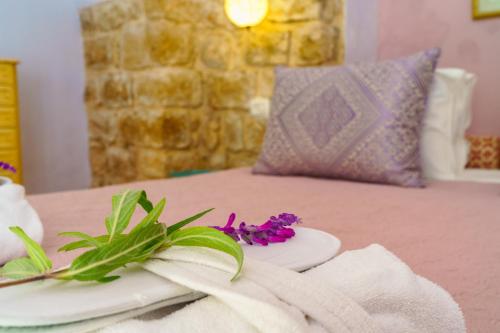 a white plate with purple flowers on a table at The Way Inn - Boutique Suites in Safed