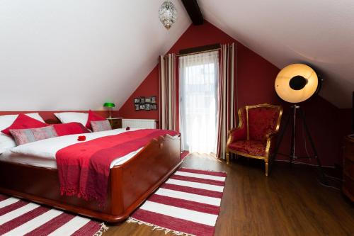 - une chambre avec des murs rouges, un lit et une chaise dans l'établissement VILLA CANTARE, à Obernburg am Main