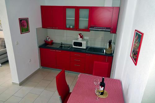 a red kitchen with a table and a microwave at Apartments Nevenka i Josko in Tučepi