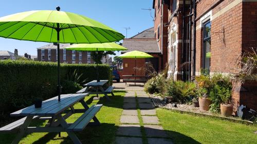 uma mesa de piquenique com um guarda-chuva verde ao lado de um edifício em The Mon Fort em Bridlington