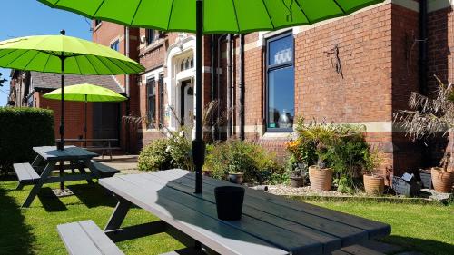 a picnic table with two green umbrellas in a yard at The Mon Fort in Bridlington