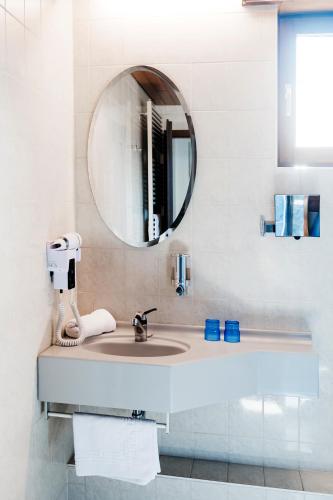a bathroom with a sink and a mirror at Logis Hôtel Restaurant Au Lion Rouge in Bartenheim