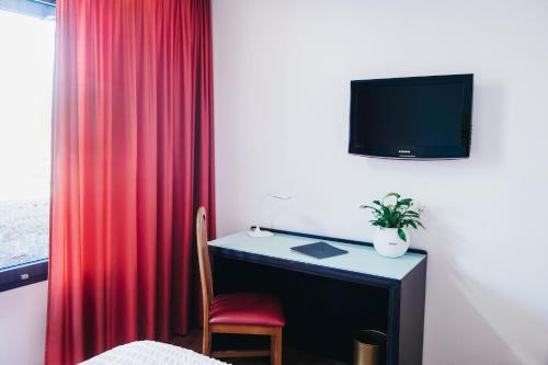 a room with a desk with a red curtain at Logis Hôtel Restaurant Au Lion Rouge in Bartenheim