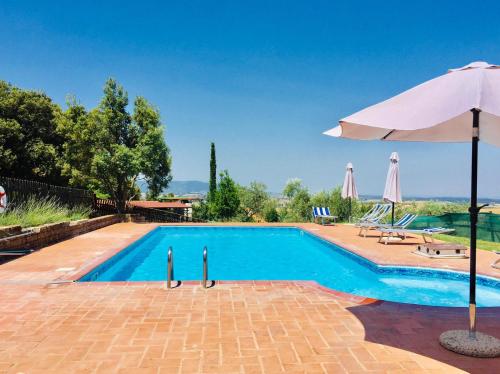 a large swimming pool with an umbrella and a patio at La Mariola Apartments in Santa Luce