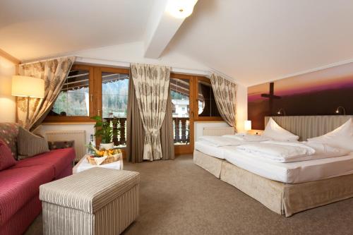 a bedroom with a large bed and a red couch at Olympia-Relax-Hotel Leonhard Stock in Finkenberg