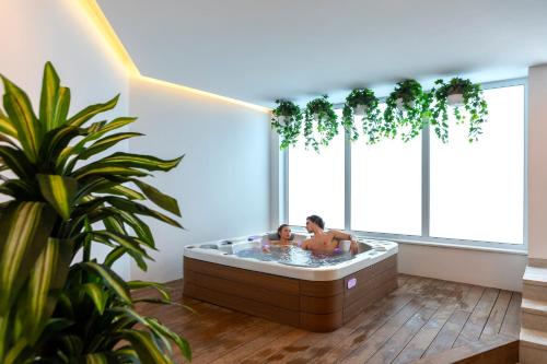 duas pessoas numa banheira de hidromassagem num quarto com plantas em Leonardo Crystal Cove Hotel & Spa – Adults only em Protaras