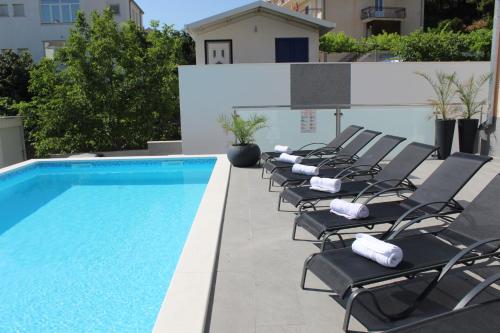 a row of chaise lounge chairs next to a swimming pool at Luxury Apartment Antoni in Podstrana