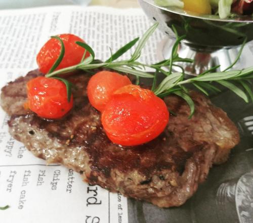 a piece of steak with tomatoes on top of it at Hotel Polonia in Biała Podlaska