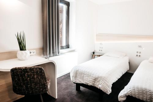 a room with two beds and a chair and a window at Logis Hôtel Restaurant Au Lion Rouge in Bartenheim