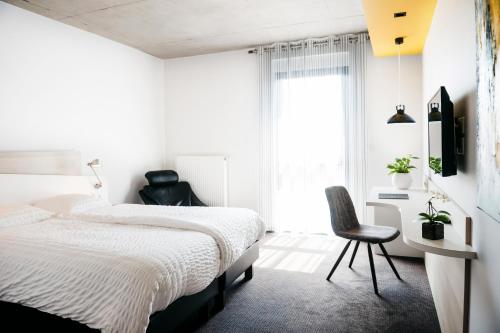 a bedroom with a bed and a desk and a chair at Logis Hôtel Restaurant Au Lion Rouge in Bartenheim