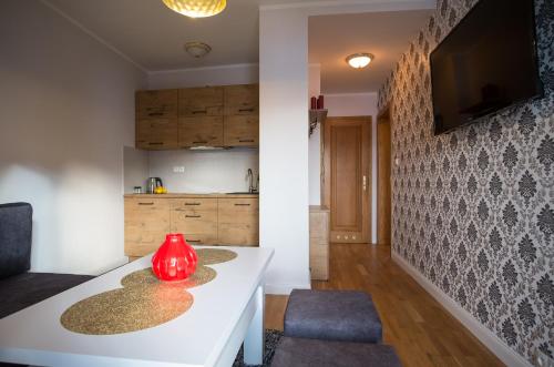 a kitchen with a white table and a red vase at Apartamenty Ciche Wzgórze Zakopane in Zakopane