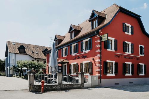 a red building with an umbrella in front of it at Logis Hôtel Restaurant Au Lion Rouge in Bartenheim