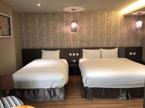 two beds in a hotel room with white sheets at Fine Hotel in Kaohsiung