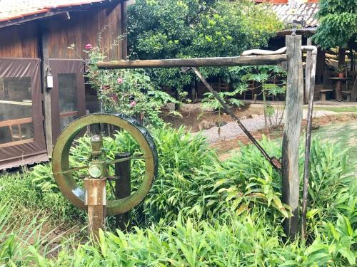 an old wheel and a wooden fence and a garden at Pousada Recanto da Siriema in Monte Alegre do Sul