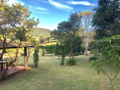 a garden with trees and a table in a field at Pousada Recanto da Siriema in Monte Alegre do Sul