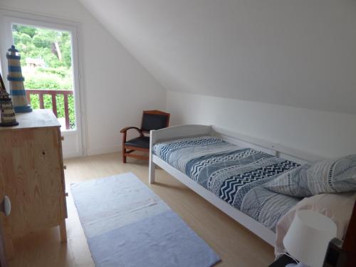 een slaapkamer met een bed, een stoel en een raam bij Gîte Le Petit Chalet avec parking gratuit in Étretat