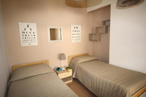 a bedroom with two beds and a lamp on a table at Appartamenti Sole 1 in Alghero