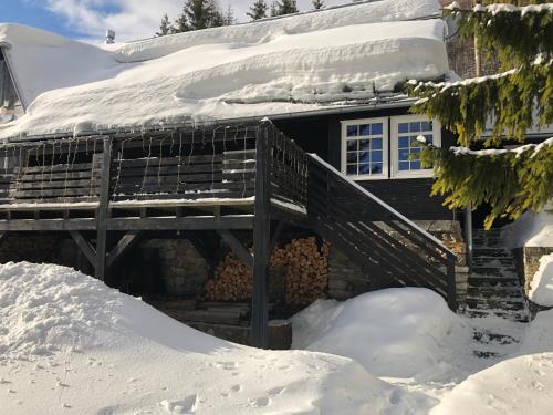 a house covered in snow with a wooden deck at Chalupa Pri vleku. in Donovaly