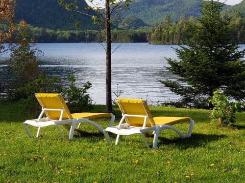 two chairs sitting in the grass near a lake at Chalet F116 Mont-Tremblant Nord in Lac-Superieur