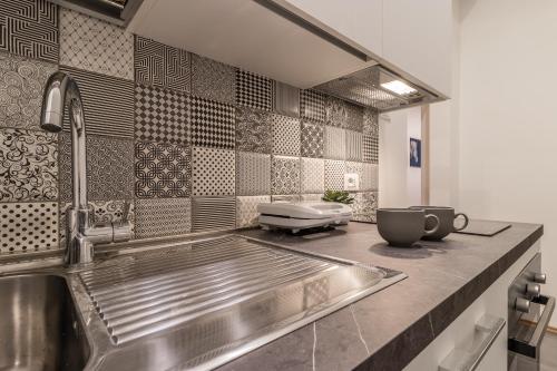 una cucina con lavandino e piastrelle in acciaio inossidabile di Elegante appartamento da 6 Blu&Oro a Trieste