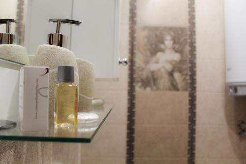 a bathroom with a bottle of perfume and a mirror at Cosmo Apartment Pleven in Pleven
