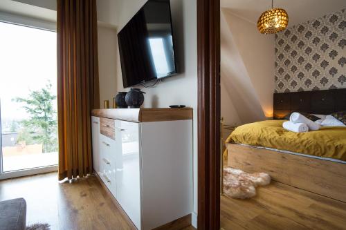 a bedroom with a bed and a tv on the wall at Apartamenty Ciche Wzgórze Zakopane in Zakopane