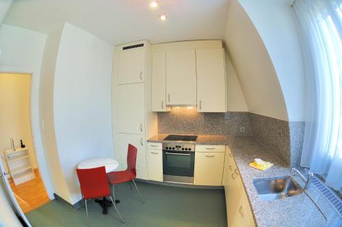 チューリッヒにあるSpacious 2-bedroom near lake - Stardust 32の小さなキッチン(白いキャビネット、赤い椅子付)