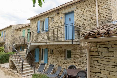 una casa de piedra con una escalera y sillas delante de ella en Gordes Le Bastidon, en Gordes