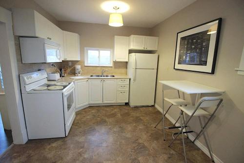 a small kitchen with white appliances and a table at Maison Doucet in Niagara Falls