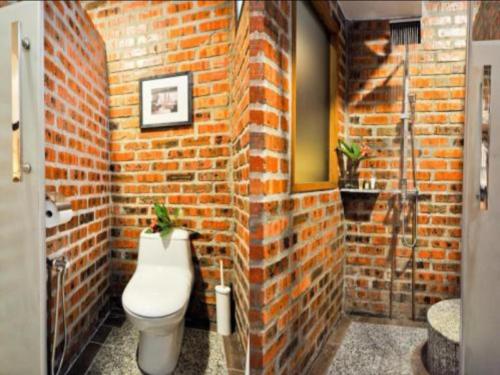 a brick bathroom with a toilet in a brick wall at Kinta Bali Villa in Ipoh