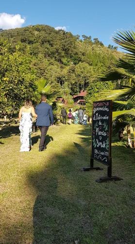 a man and woman walking through a park with a sign at Mercedes Lodge in San Ramón