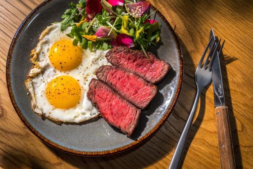 a plate of breakfast food with eggs and steak at MADE Hotel in New York