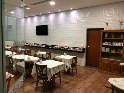 ein Esszimmer mit Tischen und einem Fernseher an der Wand in der Unterkunft Victor Plaza Formiga in Formiga