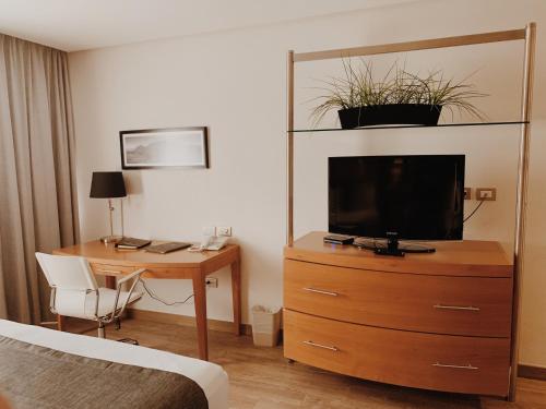 a hotel room with a desk and a television on a dresser at Hotel Mercury Inn in Querétaro