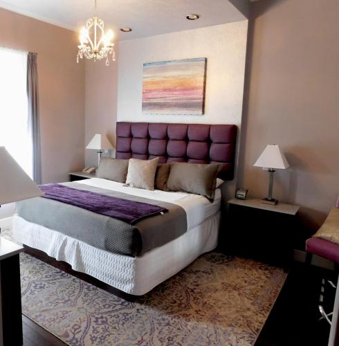 a bedroom with a large bed with a purple headboard at The Gould Hotel in Seneca Falls