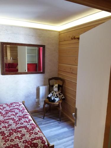 une chambre avec un lit, un miroir et une chaise dans l'établissement le Woody, à Saint-Étienne-de-Tinée