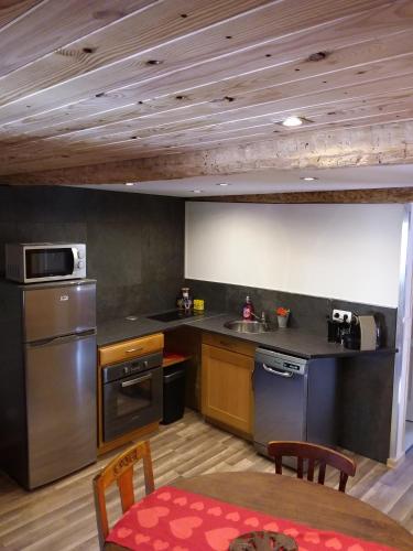 une cuisine avec des appareils en acier inoxydable et une table dans l'établissement le Woody, à Saint-Étienne-de-Tinée