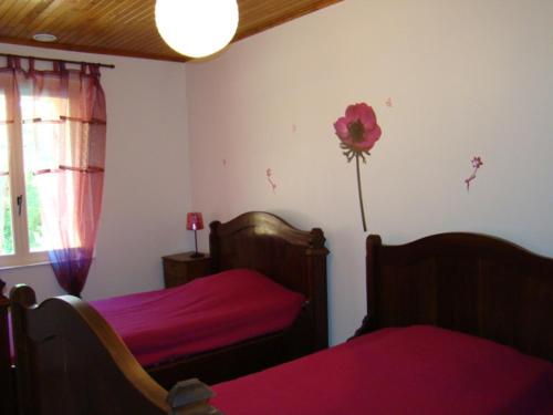 - une chambre avec 2 lits et une fleur sur le mur dans l'établissement gîte de l oustalneou, à Cuzorn