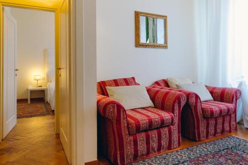a living room with a red chair and a mirror at Exclusive Aparthotel La Reunion in Ravenna