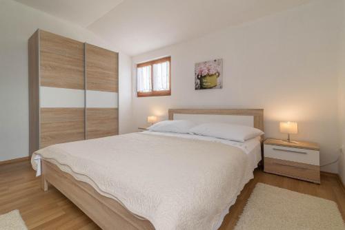 een slaapkamer met een groot wit bed en 2 lampen bij Apartment Summer in Sukošan