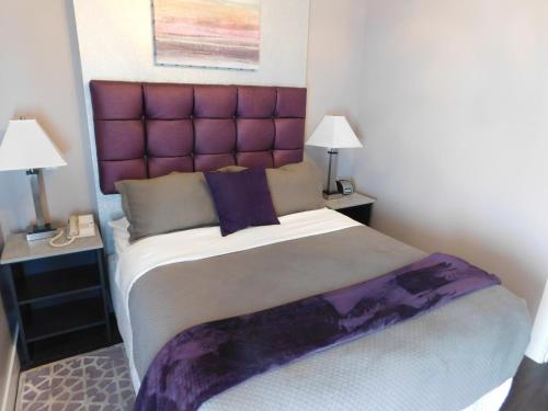 a bedroom with a large bed with a purple headboard at The Gould Hotel in Seneca Falls