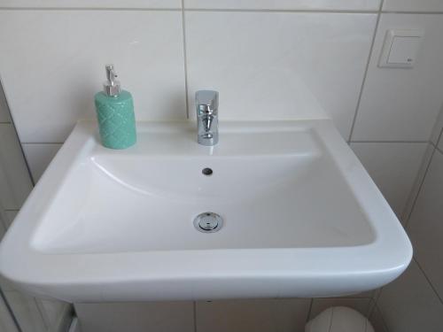 a white sink in a bathroom with a green candle on it at Hotel am Stadion VANINO cucina ITALIAN in Bielefeld